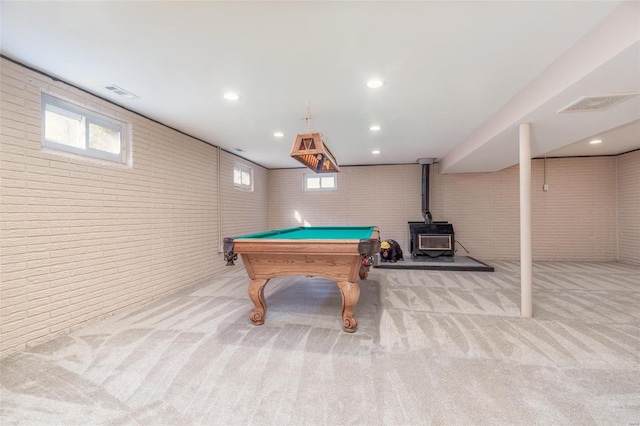 recreation room featuring brick wall, a wood stove, light carpet, and pool table