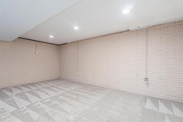 basement featuring light colored carpet and brick wall