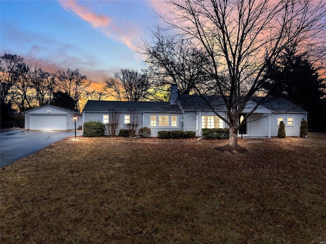 ranch-style home with a garage, a lawn, an outdoor structure, and a chimney