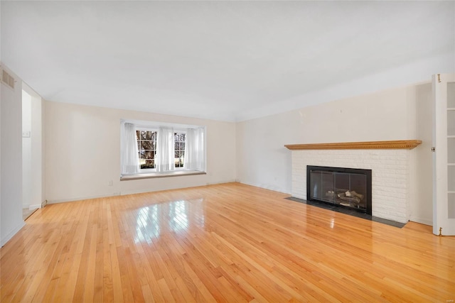 unfurnished living room with light wood finished floors, a fireplace, and visible vents