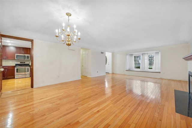 unfurnished living room featuring a fireplace with flush hearth, light wood-type flooring, a chandelier, and baseboards