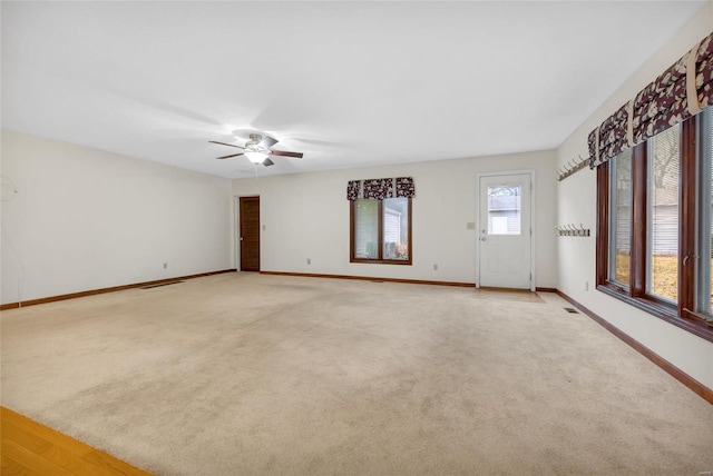 unfurnished room with visible vents, baseboards, ceiling fan, and light colored carpet