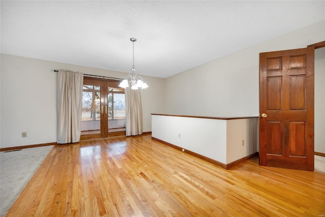 unfurnished room with baseboards, visible vents, light wood-style flooring, and a notable chandelier