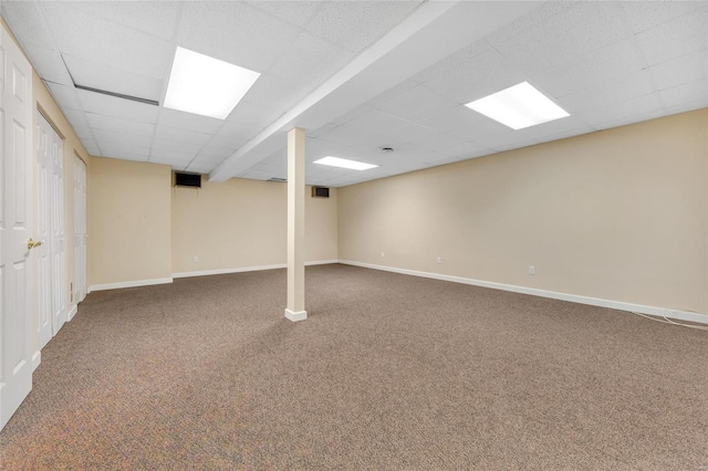 finished basement with a paneled ceiling, baseboards, and carpet flooring