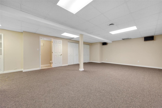 finished below grade area featuring a drop ceiling, carpet flooring, and baseboards