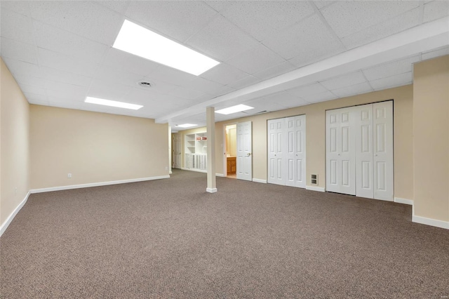 finished basement with a paneled ceiling, carpet flooring, and baseboards