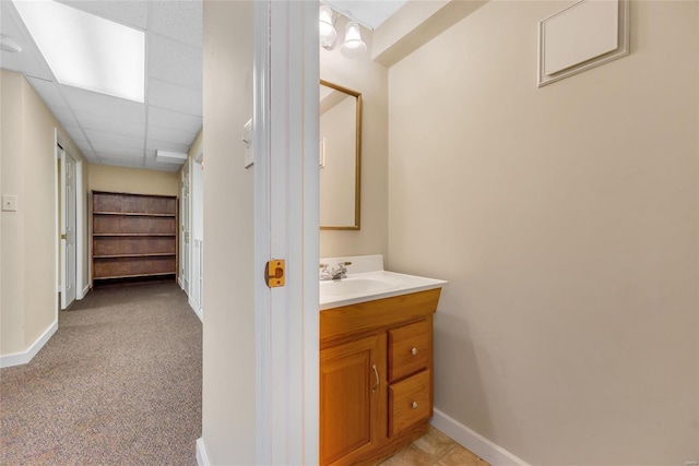 bathroom with vanity, a paneled ceiling, and baseboards