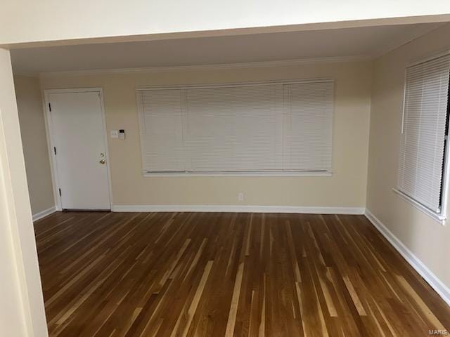 empty room with baseboards, ornamental molding, and dark wood-type flooring