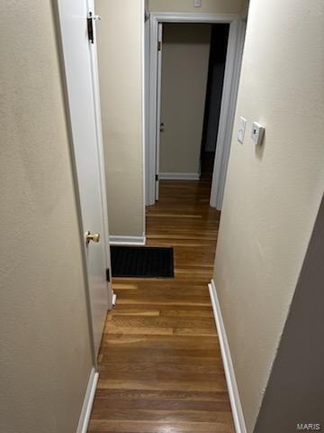 corridor featuring visible vents, baseboards, and wood finished floors