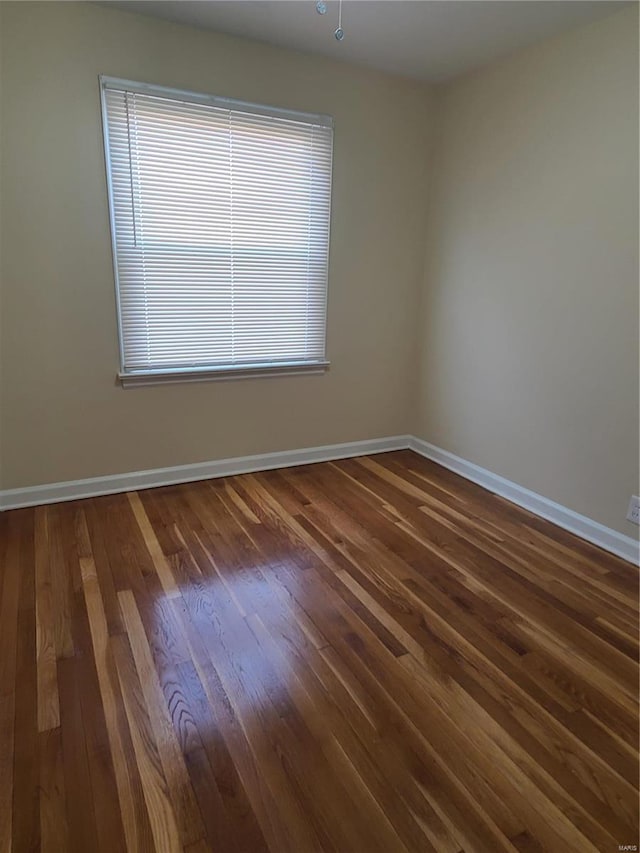 unfurnished room with baseboards and dark wood-type flooring