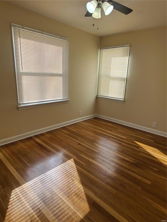 spare room featuring baseboards, ceiling fan, and dark wood-style floors