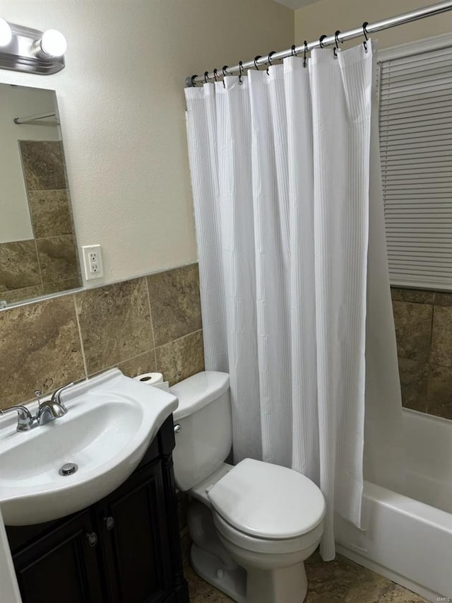 full bathroom with vanity, toilet, tile walls, and shower / bathtub combination with curtain