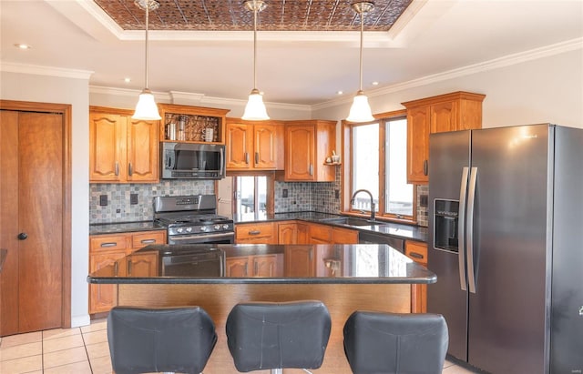 kitchen featuring a kitchen island, decorative light fixtures, a raised ceiling, sink, and stainless steel appliances