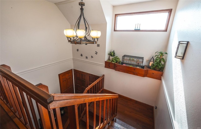 staircase featuring hardwood / wood-style flooring, vaulted ceiling, and a chandelier