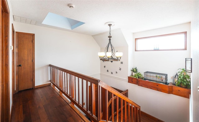 hallway with lofted ceiling, dark hardwood / wood-style floors, a chandelier, and a textured ceiling