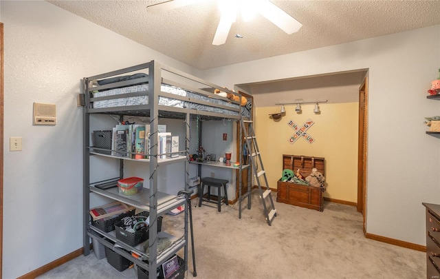 carpeted bedroom featuring ceiling fan, track lighting, and a textured ceiling