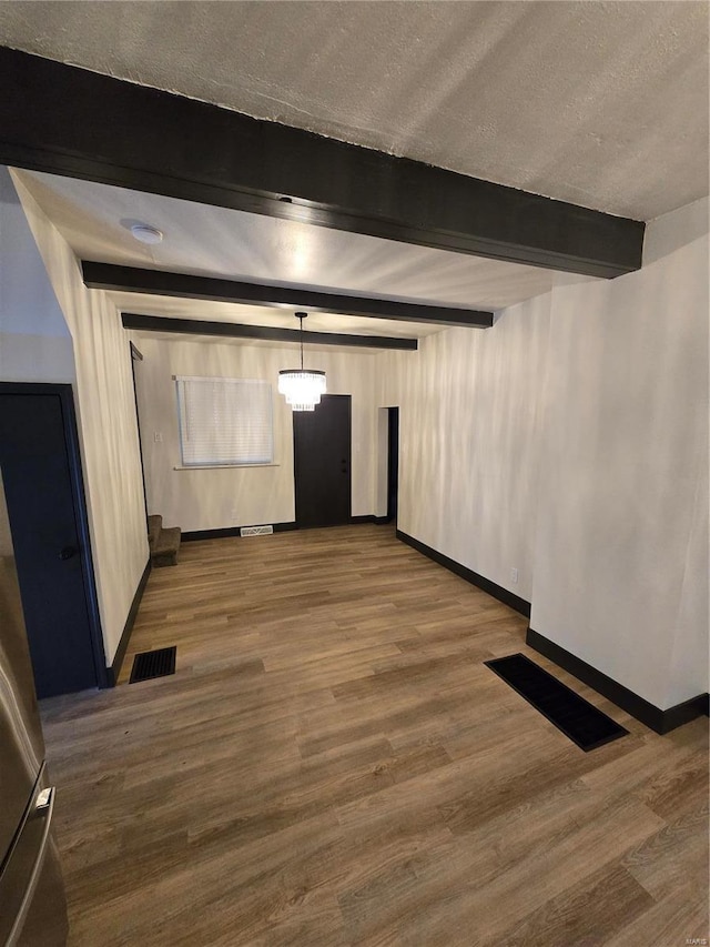 interior space featuring beamed ceiling, wood-type flooring, and a textured ceiling