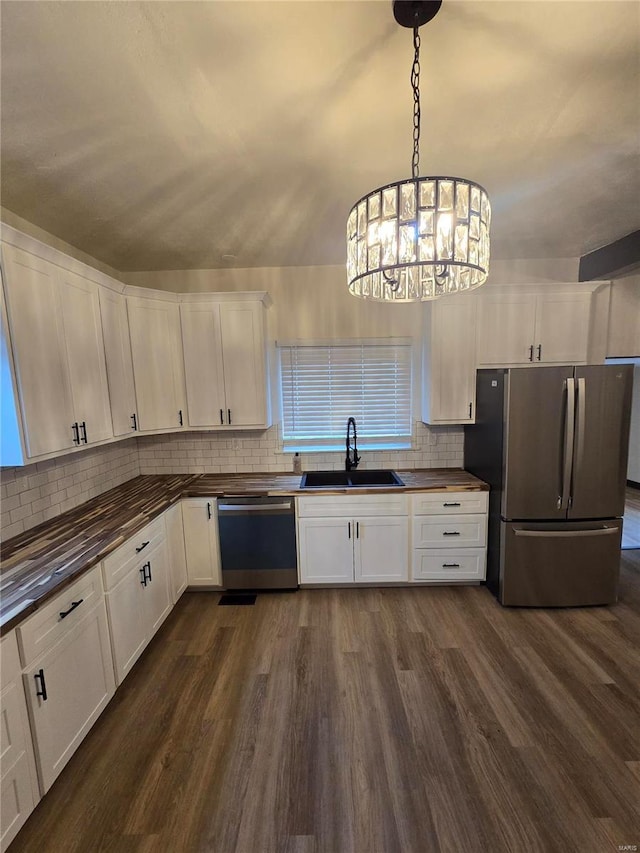 kitchen featuring sink, appliances with stainless steel finishes, hanging light fixtures, dark hardwood / wood-style floors, and white cabinets