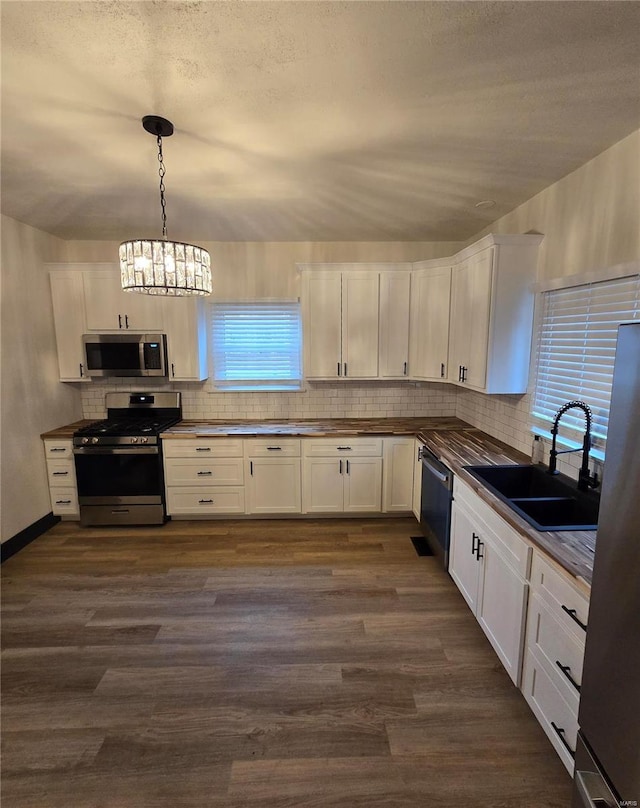 kitchen featuring sink, hanging light fixtures, dark hardwood / wood-style flooring, stainless steel appliances, and white cabinets