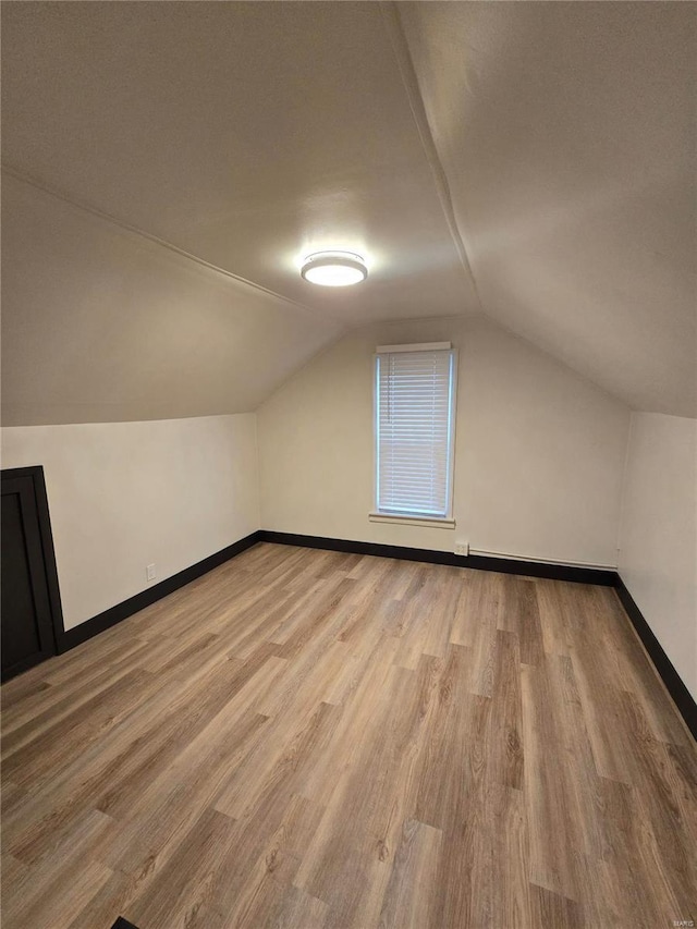 bonus room featuring vaulted ceiling and light wood-type flooring