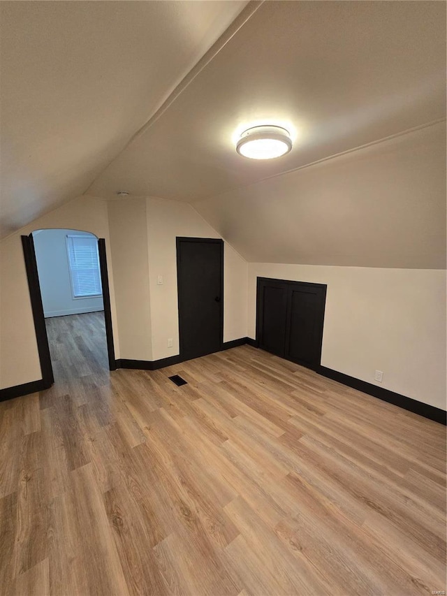 additional living space featuring lofted ceiling and light hardwood / wood-style floors