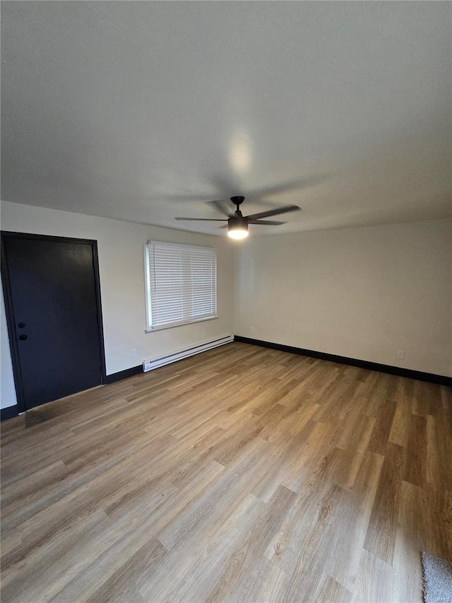 spare room featuring a baseboard radiator, ceiling fan, and light hardwood / wood-style floors