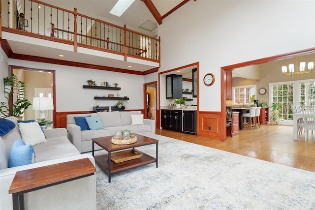 living room featuring crown molding, light hardwood / wood-style flooring, a chandelier, and a high ceiling