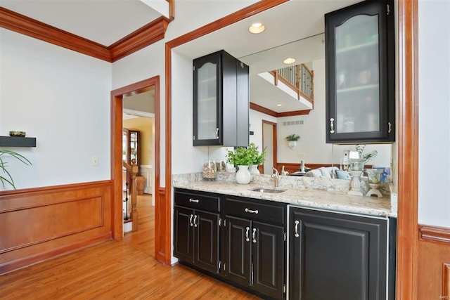 bar featuring sink, crown molding, light hardwood / wood-style flooring, and light stone countertops