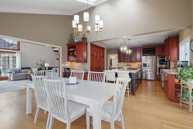 dining area featuring ornamental molding, a chandelier, light hardwood / wood-style floors, and a high ceiling