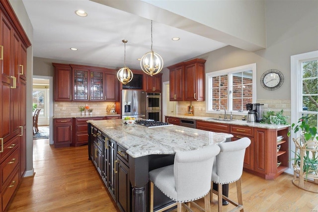 kitchen with a kitchen island, sink, hanging light fixtures, light hardwood / wood-style floors, and stainless steel appliances