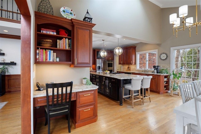 kitchen featuring appliances with stainless steel finishes, decorative light fixtures, a kitchen bar, a center island, and light hardwood / wood-style floors