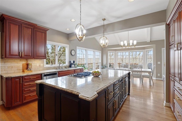 kitchen with hanging light fixtures, a kitchen island, appliances with stainless steel finishes, and sink