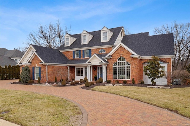 view of front of home featuring a garage, a front yard, and central air condition unit