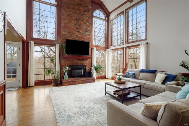 living room featuring plenty of natural light, a towering ceiling, a fireplace, and light wood-type flooring