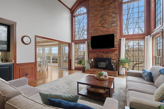 living room with high vaulted ceiling, a brick fireplace, and light wood-type flooring