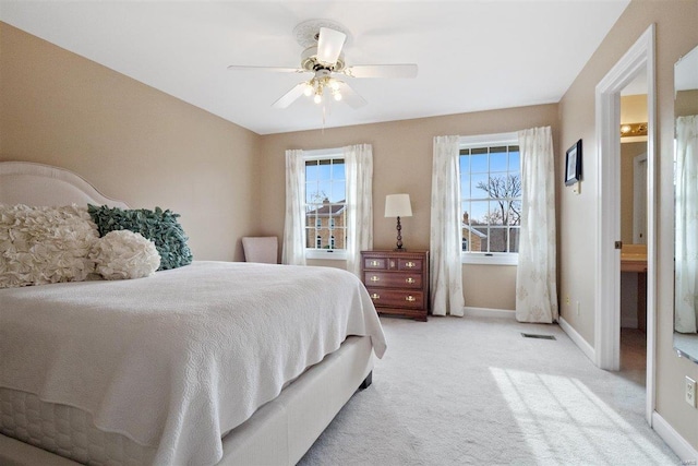 bedroom with ceiling fan, light carpet, and multiple windows