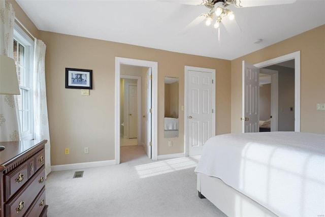 bedroom with ceiling fan, light colored carpet, and ensuite bathroom