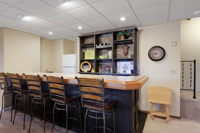 bar featuring white refrigerator and a paneled ceiling