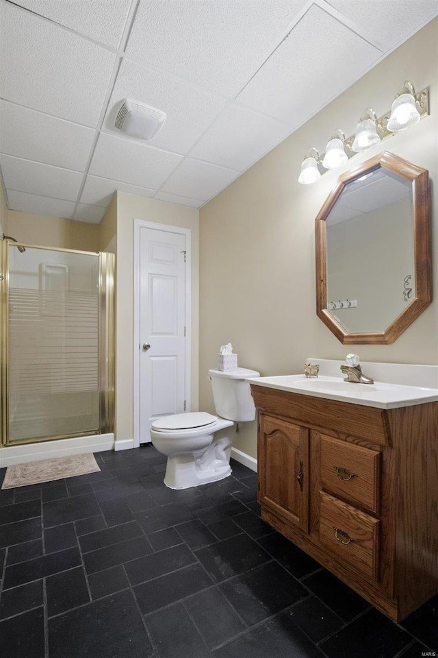 bathroom featuring vanity, a shower with shower door, a drop ceiling, and toilet