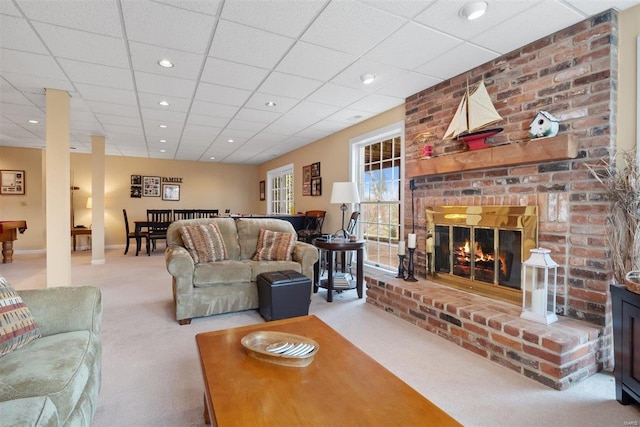 carpeted living room featuring a drop ceiling and a fireplace