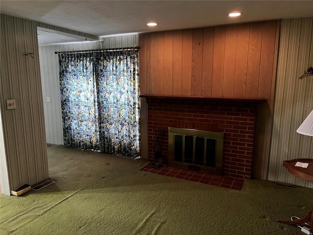 unfurnished living room featuring a brick fireplace, wooden walls, and dark carpet