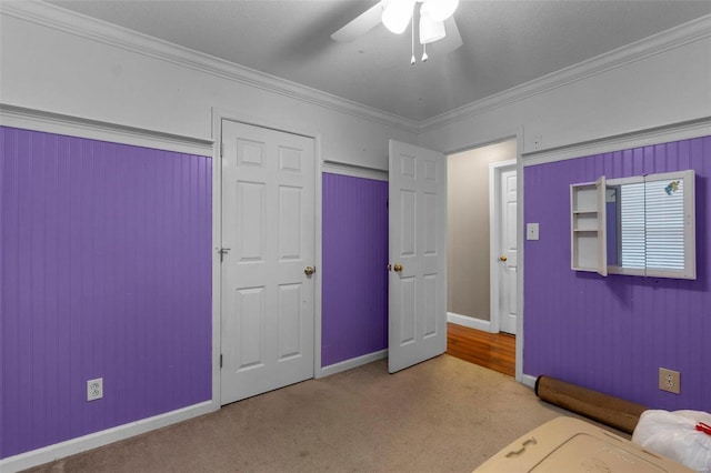 unfurnished bedroom featuring ceiling fan, ornamental molding, and carpet floors