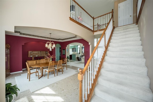 dining room featuring stairway, arched walkways, a towering ceiling, and an inviting chandelier