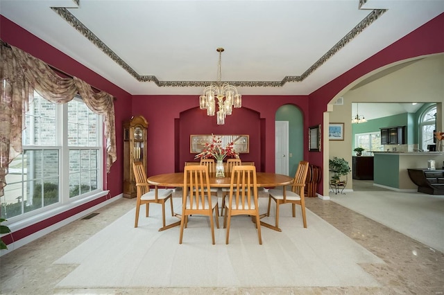 dining space with baseboards, visible vents, arched walkways, and a notable chandelier