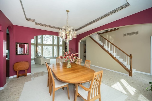 dining room with arched walkways, visible vents, an inviting chandelier, and stairs