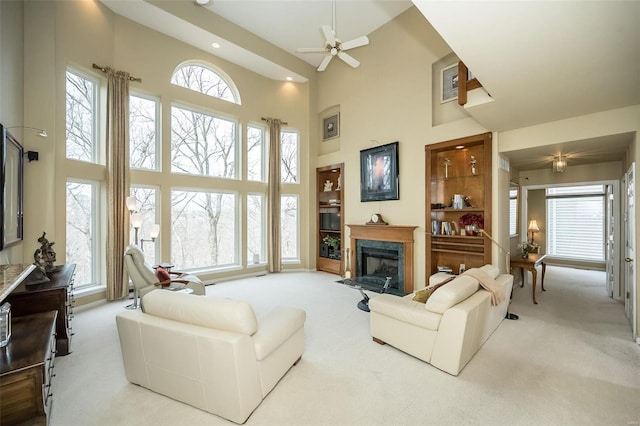 living room with a towering ceiling, carpet, and a high end fireplace