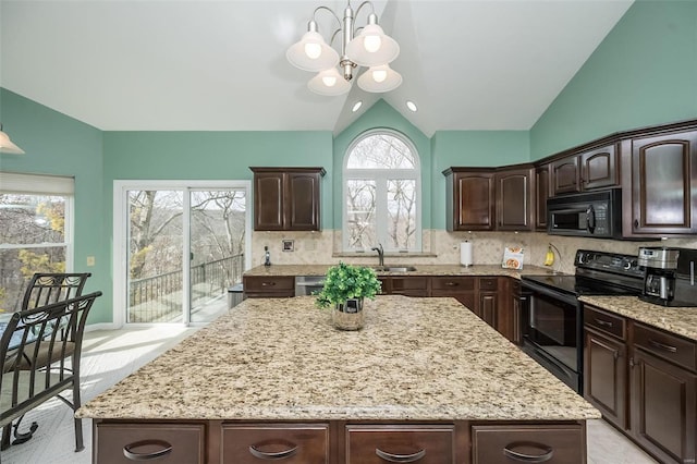 kitchen featuring a kitchen island, vaulted ceiling, dark brown cabinetry, light stone countertops, and black appliances