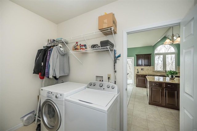 washroom with laundry area, light tile patterned floors, washer and dryer, and an inviting chandelier