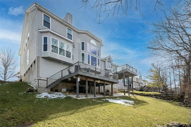 back of property with a wooden deck, stairs, a chimney, and a yard