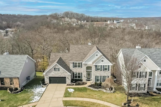 view of front of property with driveway, stone siding, a garage, and a front lawn